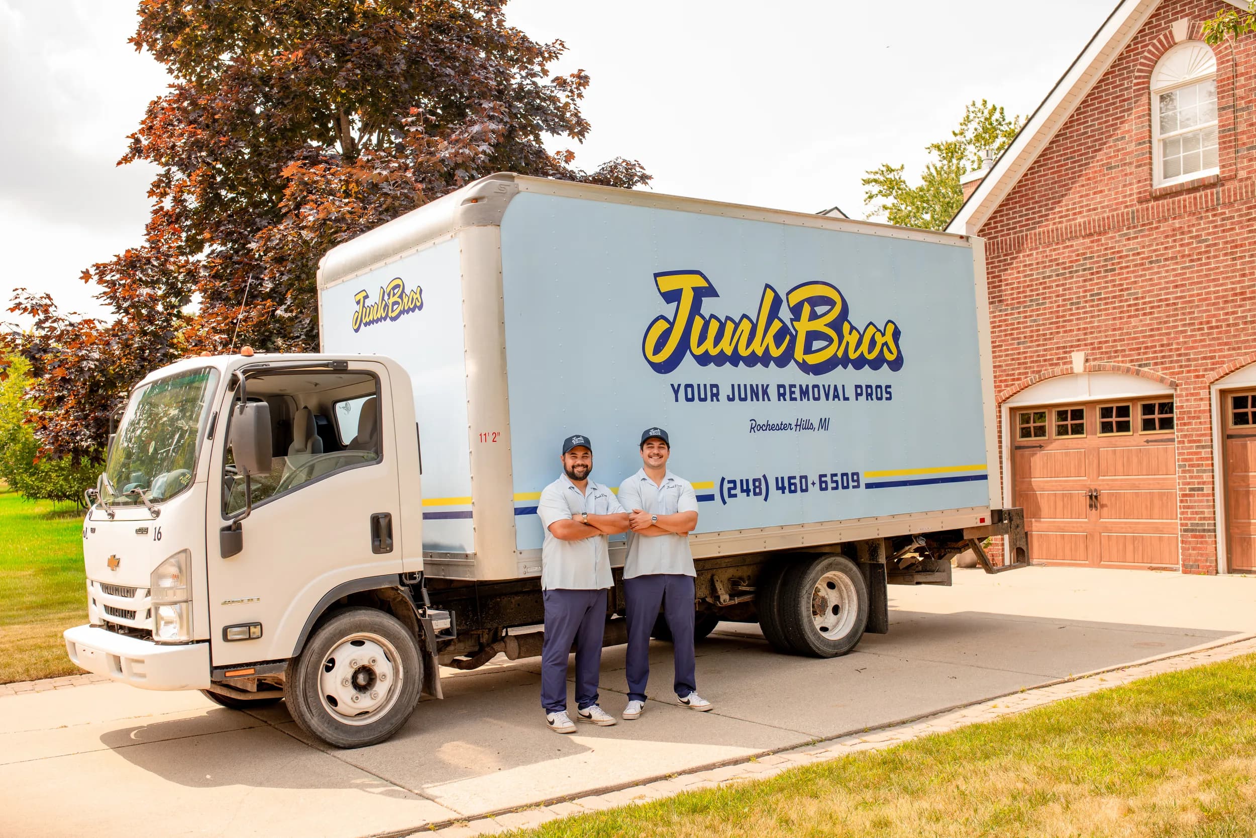 Matt and Brad standing in front of the Junk Bros box truck in a customer's driveway