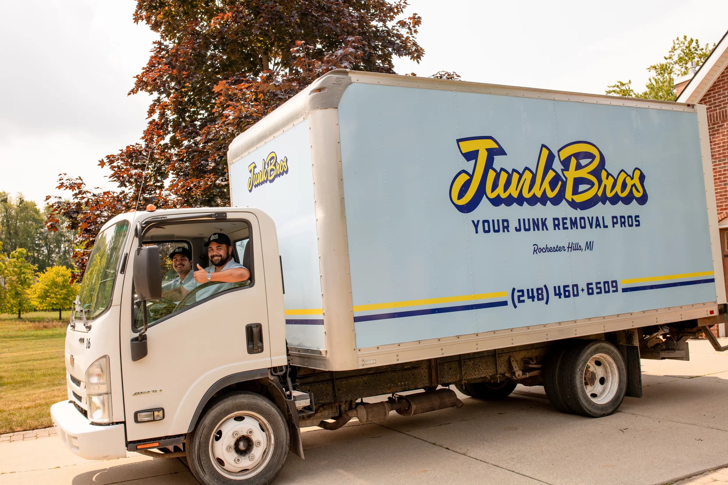 The Junk Bros truck in a Rochester Hills driveway, Matt and Brad in the cab